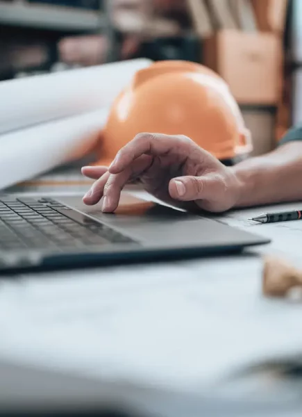 Engineering working with drawings inspection on laptop  in the office and Calculator, triangle ruler, safety glasses, compass, vernier caliper on Blueprint. Engineer, Architect, Industry and factory concept.